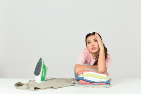 Attractive young woman looking tired of ironing