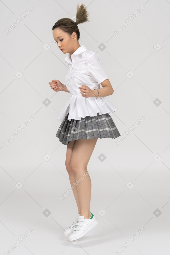 Mulher jovem asiática pulando de lado para a câmera