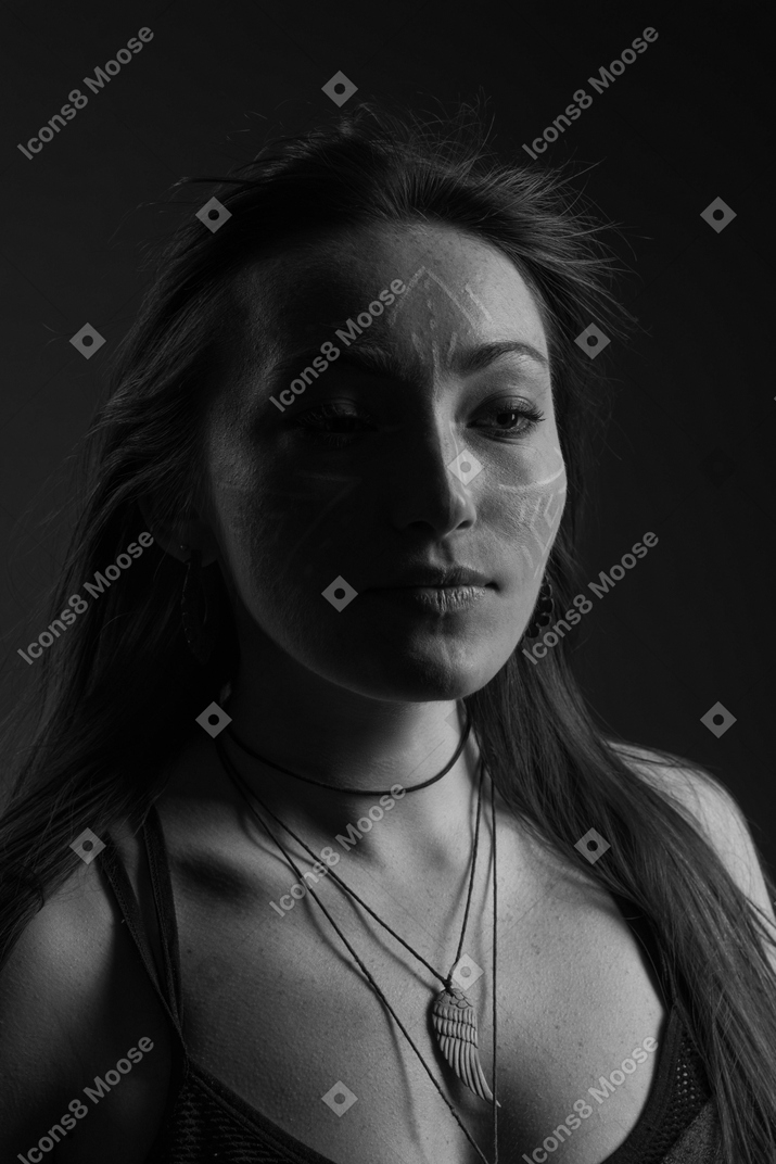Head to shoulder noir portrait of a young female with face art looking aside
