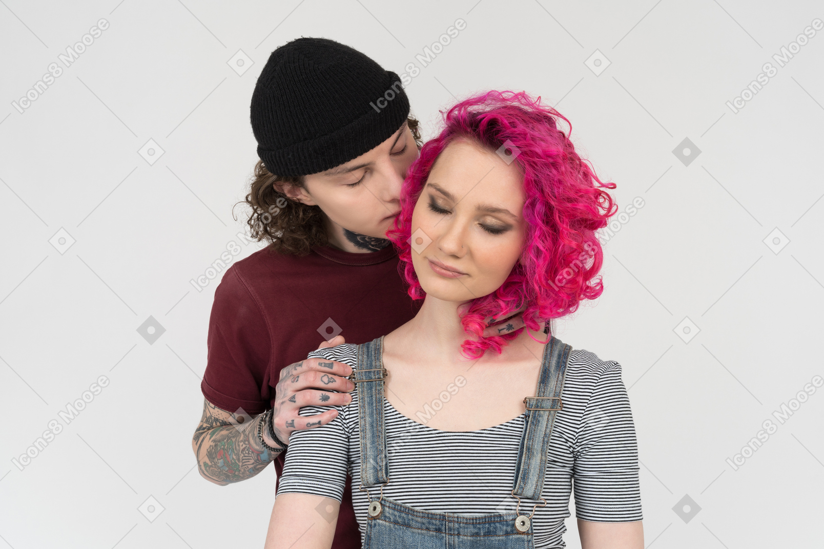 Young man standing behind his girlfriend whispers to her ear