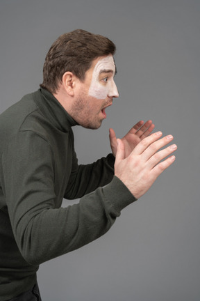 Side view of an astonished male football fan raising hands