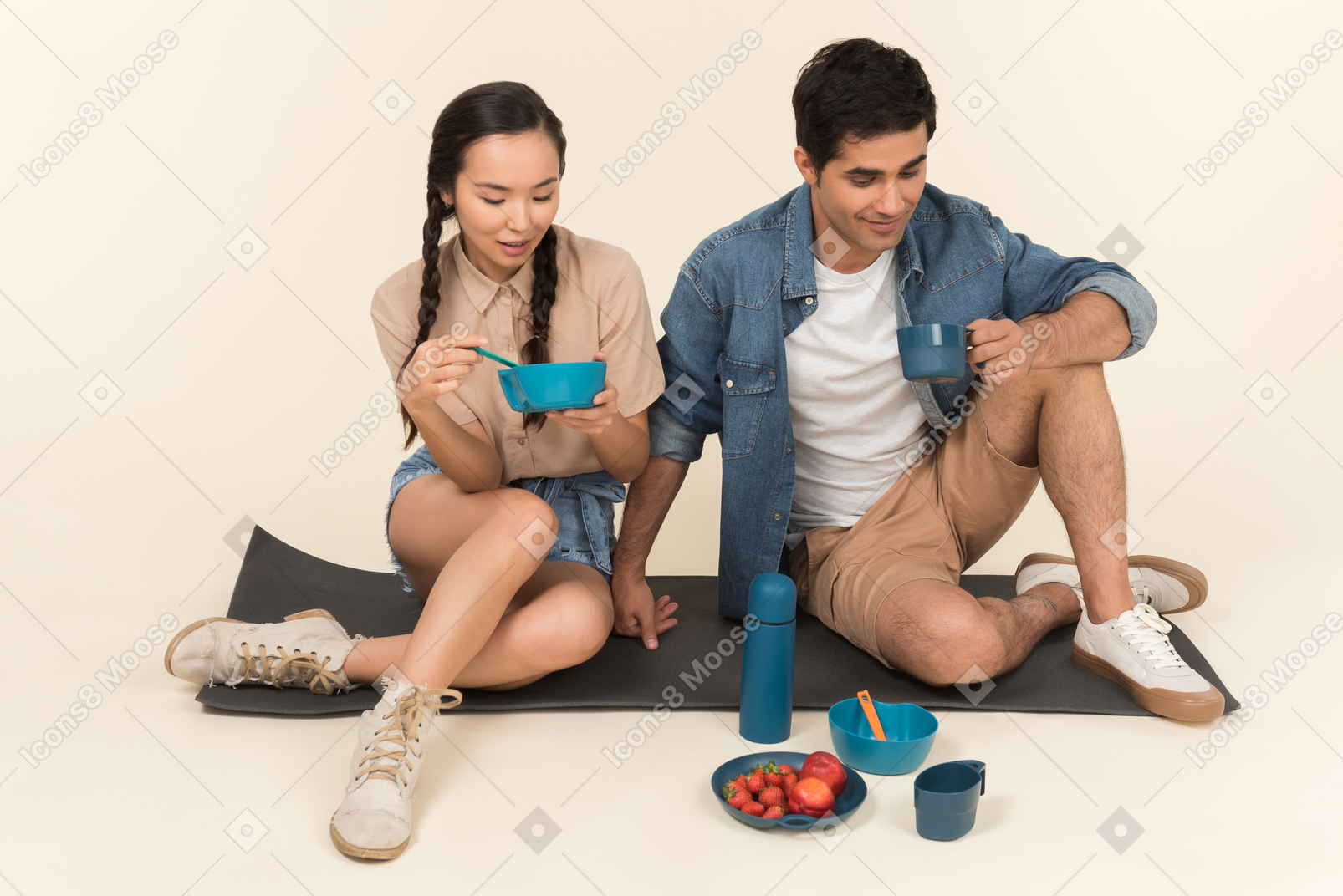 Young interracial couple sitting on karimat and eating