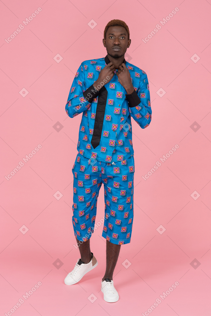 Schwarzer mann im blauen pyjama, der auf dem rosa hintergrund steht
