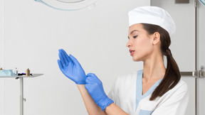 A woman wearing blue gloves and a medical hat