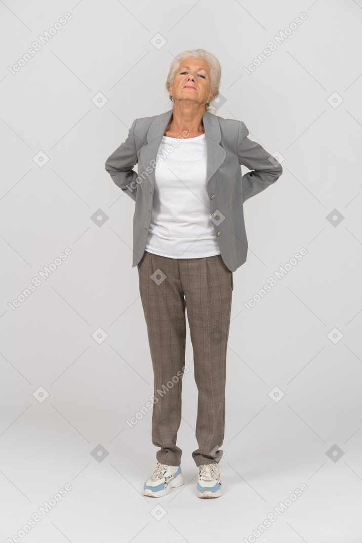 Vorderansicht einer alten dame im anzug mit rückenschmerzen