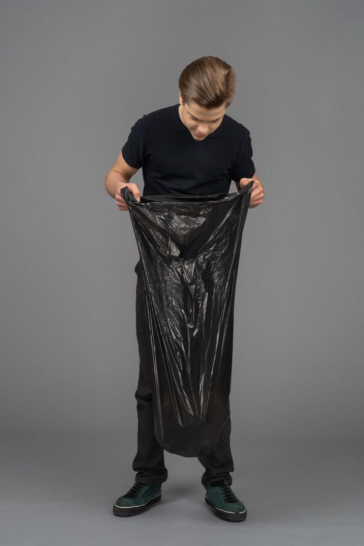 A young man looking inside a trash bag