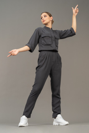 Front view of a young woman in a jumpsuit outstretching her arm