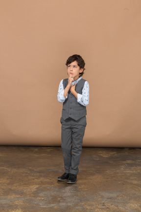 Вид спереди задумчивого мальчика в сером костюме