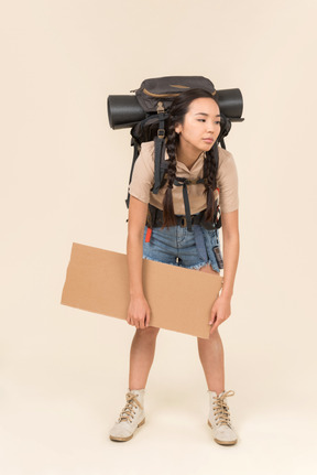 Tired looking young female hitchhiker holding paper card