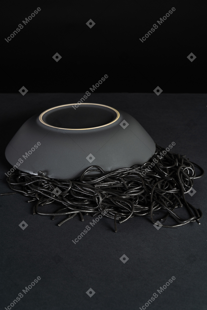 Flipped over plate with black pasta on dark background