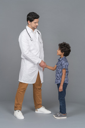 Médico e criança apertando as mãos