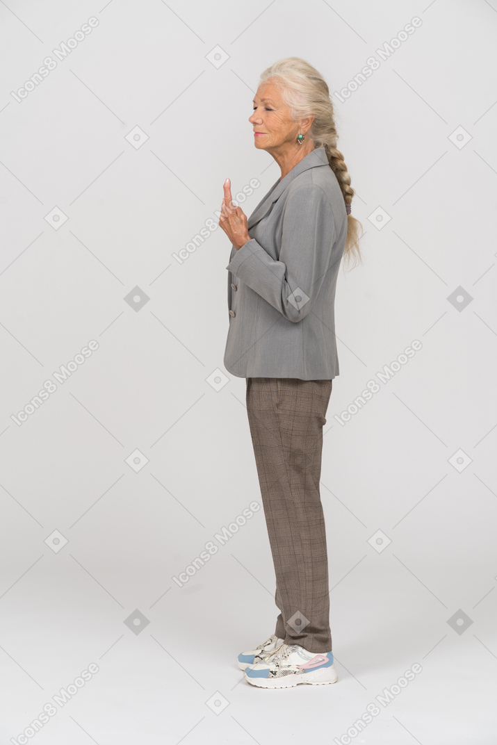 Вид сбоку пожилой дамы в костюме, указывающей пальцем
