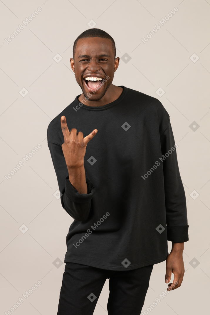 Excited young man showing hand horns