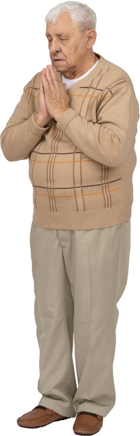 Vista frontal de um velho em roupas casuais de mãos dadas em gesto de oração