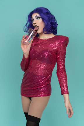 Porträt einer drag queen, die einen schluck aus einem plastikbecher nimmt