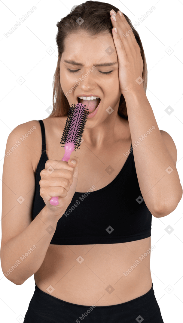 Front view of a funny singing young woman holding hairbrush