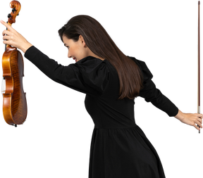 Vue de trois quarts arrière d'une joueuse de violon en robe noire faisant un arc