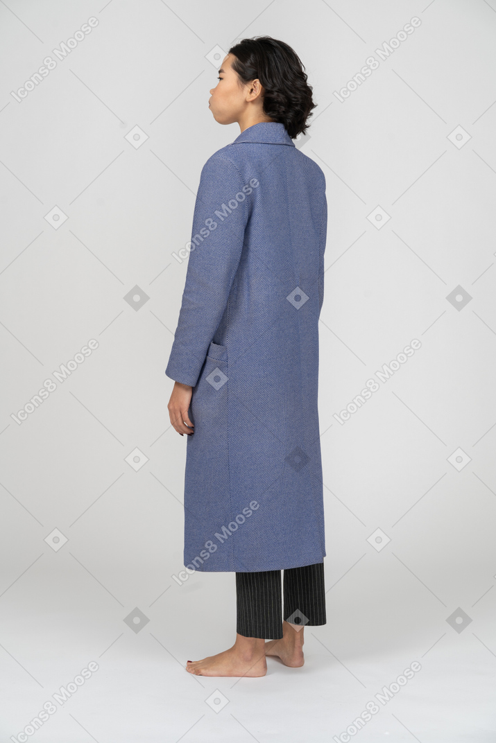뺨이 부풀어 오른 파란 코트를 입은 여성의 뒷모습