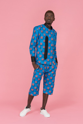 Black man in blue pajamas standing on pink background