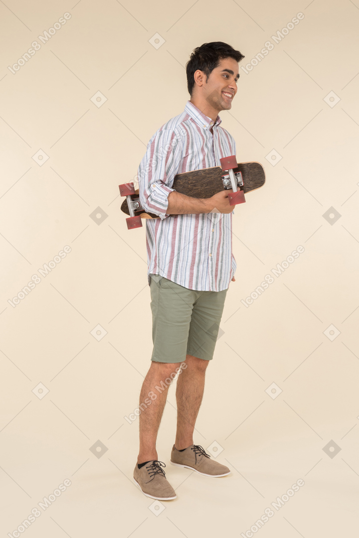 Молодой кавказский парень держит скейт