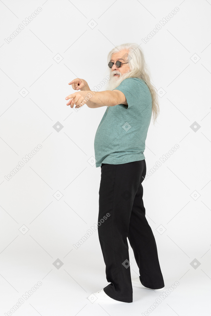 Vue latérale du vieil homme à lunettes de soleil pointant à deux mains
