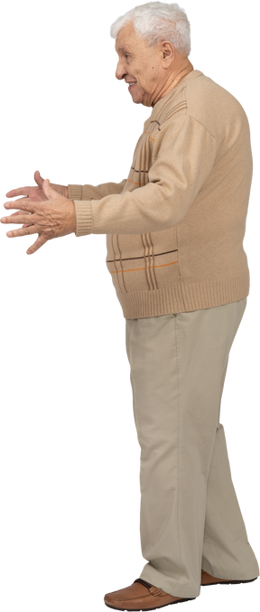 Side view of a happy old man in casual clothes standing with outstretched arms