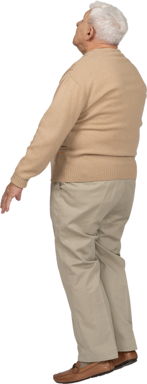 Side view of an old man in casual clothes standing on toes and looking up