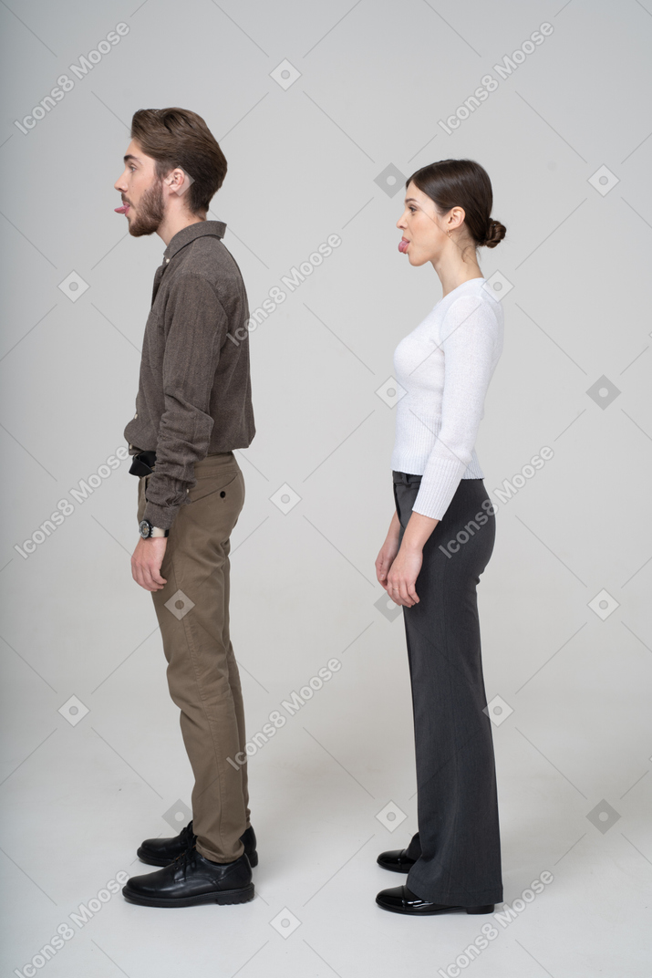 一对年轻夫妇在显示舌头的办公服装的侧视图