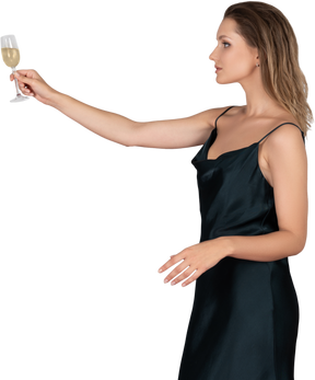 Vista lateral de una mujer joven en bata de noche extendiendo el brazo con una copa de champán