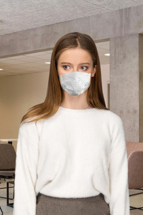A woman wearing a face mask standing in a room