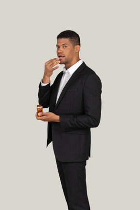 African american in black suit holding bottle of pills