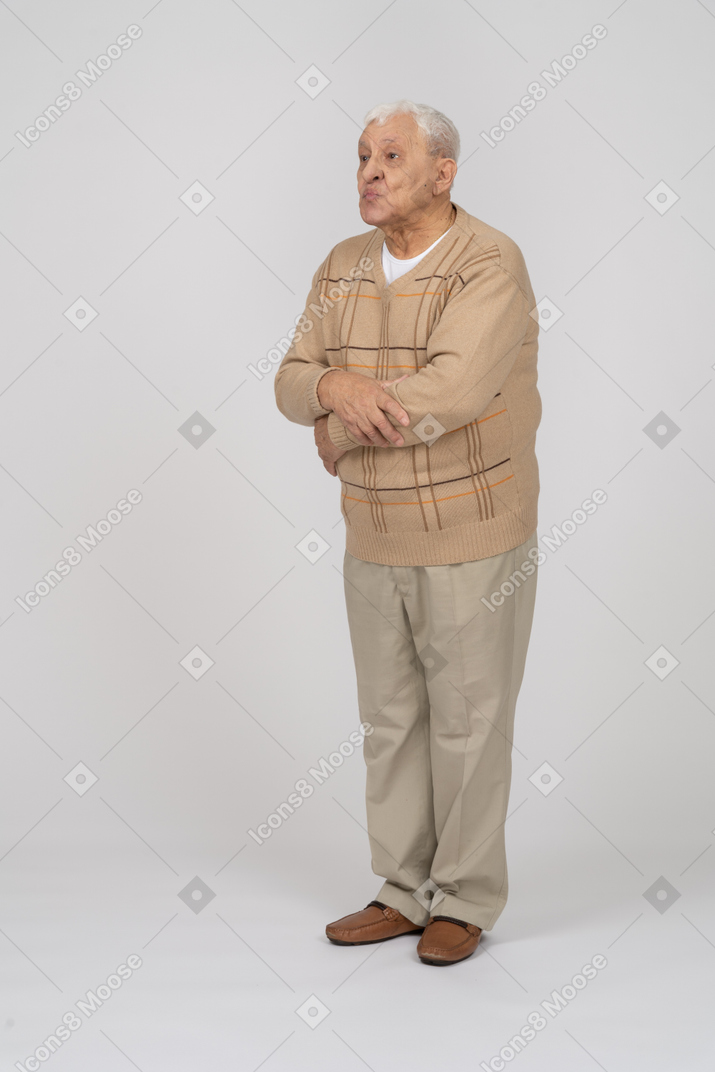 Front view of an old man in casual clothes blowing a kiss