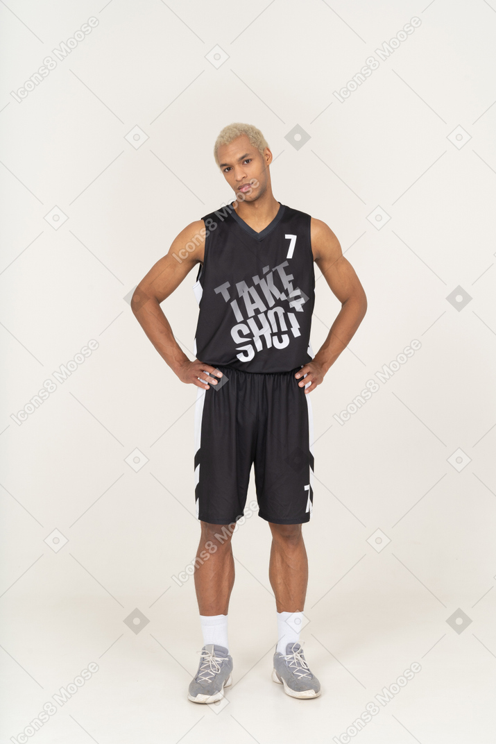 Front view of a young male basketball player putting hands on hips & looking at camera