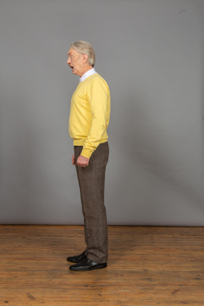 Vista lateral de um homem falando em um pulôver amarelo