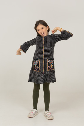 Vista frontale di una bambina in abito che allunga la schiena e le braccia