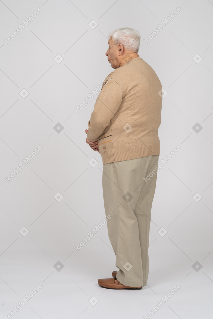 Side view of an old man in casual clothes making faces