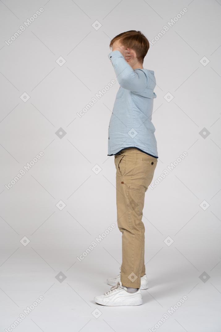 Vue latérale d'un garçon posant avec les mains sur la tête