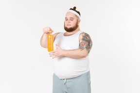 A fat sportsman opening a bottle of orange drink