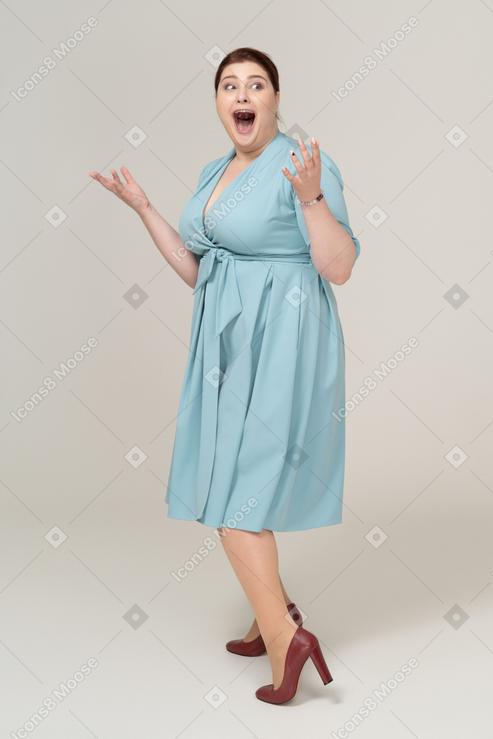 Mulher impressionada em vestido azul posando de perfil