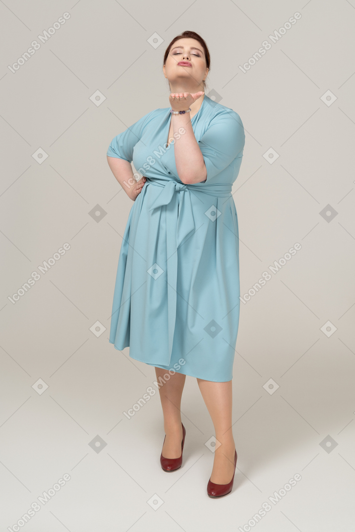 Вид спереди женщины в синем платье, отправляющей воздушный поцелуй