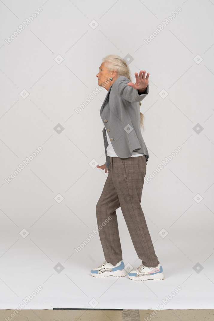 Side view of an old lady in suit balancing with outstretched arms