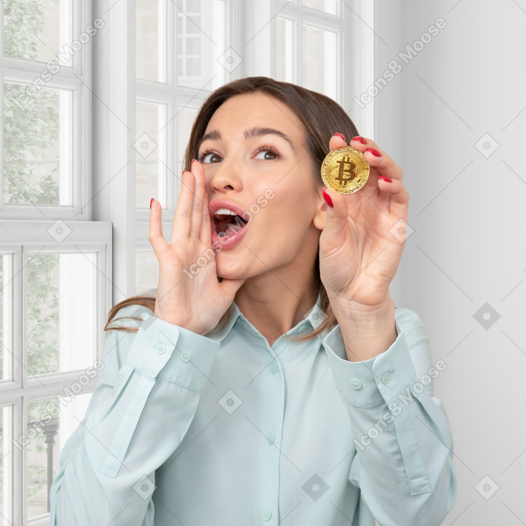 Женщина держит монету биткойн