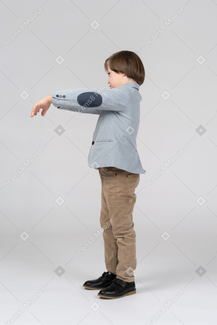 Boy in gray jacket outstretching his arms