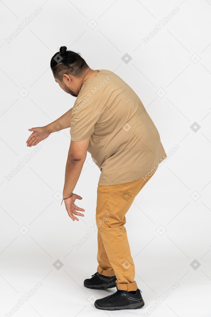 Hombre asiático de talla grande agachándose con la mano extendida
