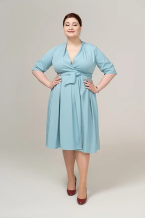 Front view of a woman in blue dress posing with hands on hips