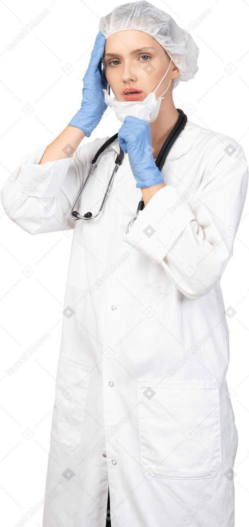 Вид в три четверти молодой женщины-врача, надевающей маску и смотрящей в камеру