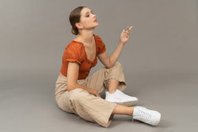 Young woman sits with raised hand