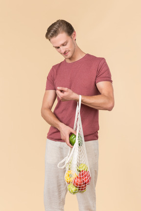 Young guy holding a string bag with groceries