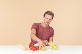 Young guy putting fruits and vegetables into a string bag