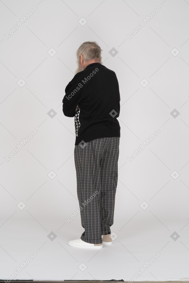 Vista traseira do homem idoso em pé com os braços cruzados
